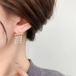Macro detail of cascading gold tassel earrings with cubic zirconia on model