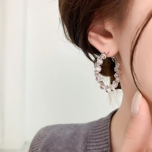 Gros plan de boucles d'oreilles créoles argentées avec zircons brillants sur modèle