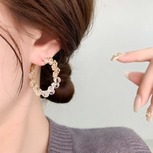 Élégantes boucles d'oreilles créoles dorées avec cristaux de zircon sur un mannequin