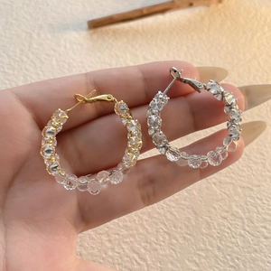 Boucles d'oreilles créoles dorées et argentées avec cristaux brillants sur fond beige