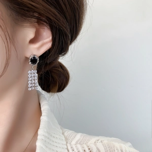 Close-up of elegant silver drop earrings with black zircon and pavé diamond tassels
