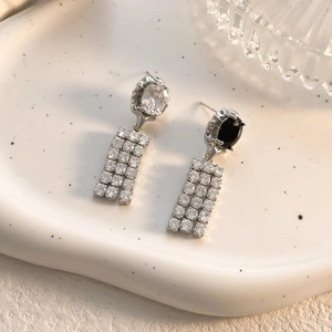 Detail view of asymmetric vintage earrings with black zircon and chain tassels on ceramic