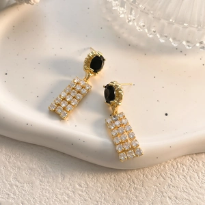 Detail of elegant gold earrings featuring black oval stones and diamond-set fringe