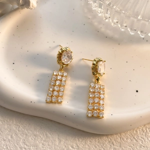 Detailed macro view of elegant gold-plated drop earrings featuring clear zircon stones