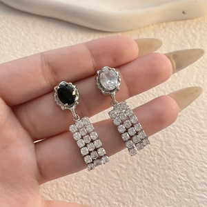 Detail of silver drop earrings with black zircon and three-row rhinestone chain tassels