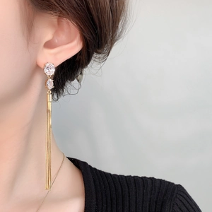 Detail of long gold fringe tassel earrings with zircon studs worn by a model