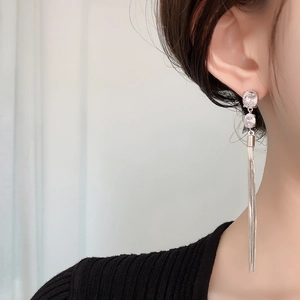 Close-up of elegant silver tassel earrings with round cubic zirconia on female model