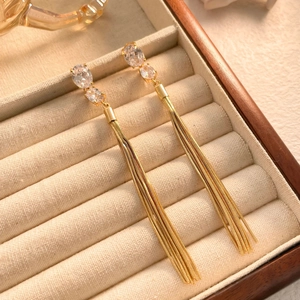 Detailed close-up of golden tassel earrings with sparkling zircon studs on velvet