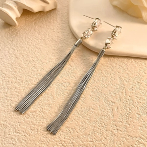 Detailed view of silver tassel earrings with three oval cubic zirconia stones on textured base