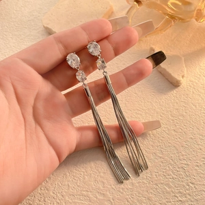 Close-up of long tassel earrings with sparkling zircon stones and silver snake chains