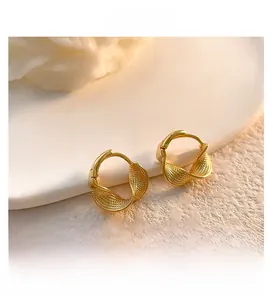 Close-up of golden braided hoop earrings with textured finish on a stone surface