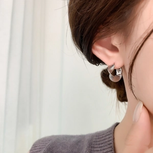 Minimalist silver braided hoop earrings with textured metal finish shown on model