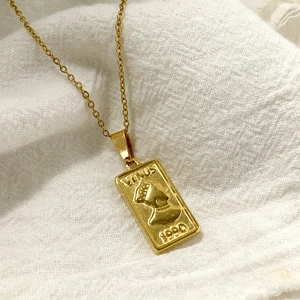 Macro detail of gold Venus portrait pendant necklace with 1990 relief on linen texture