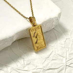 Gold Venus coin necklace with rectangular relief pendant on a minimalist white background