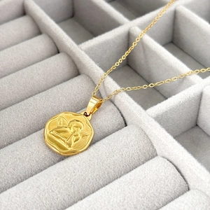 Détail macro du collier Saint Benoît doré avec pendentif ange chérubin gaufré