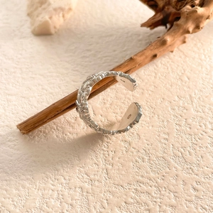 Anello regolabile in argento martellato retrò presentato su un ramo di legno naturale