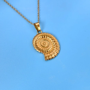 Golden nautilus shell pendant necklace on blue background featuring a delicate link chain