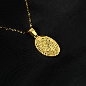 Macro shot of gold-plated St. Michael relief pendant on black textured background