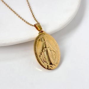 Vintage gold oval miraculous medal necklace in stainless steel on a white surface