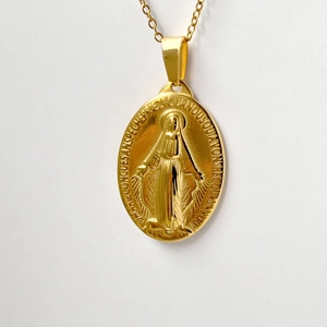 Macro shot of oval gold Virgin Mary Miracle Medal pendant with classic link chain detail