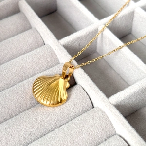 Détail d'un collier pendentif coquillage plaqué or 18 carats sur un porte-bijoux