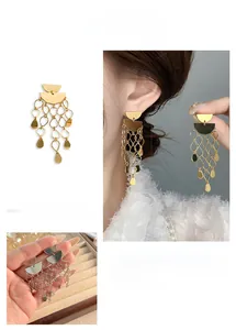 Détail de boucles d'oreilles pendantes géométriques à glands en or et argent