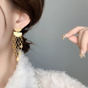 Gros plan détaillé de boucles d'oreilles pendantes dorées 18K avec pampilles sur un modèle