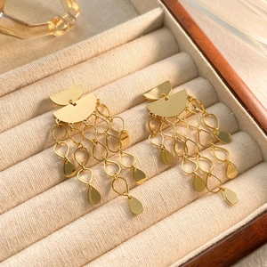 Détail de boucles d'oreilles pompons plaquées or 18 carats sur boîte à bijoux