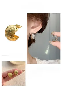 Detailed view of C-shaped earrings with woven texture in gold and silver finish
