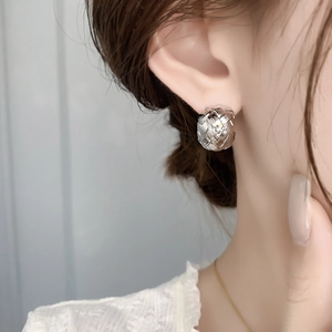 Close-up detail of silver woven texture ball stud earrings worn by a model