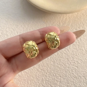 Retro hollow braided texture stud earrings in gold finish displayed on a hand