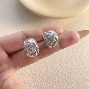 Detailed view of silver oval earrings with intricate woven texture and high-end finish
