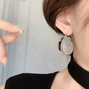 Detail of silver teardrop earring with intricate hollow mesh design worn by a model