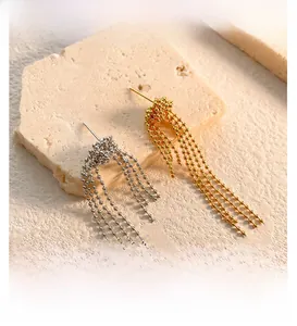 Macro detail of gold and silver beaded tassel earrings on a textured stone surface