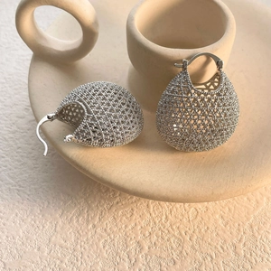 Macro shot of silver woven hollow drop earrings with intricate lattice texture details