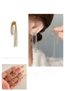 Detailed close-up of fringe tassel bead earrings in polished gold and silver metal finishes