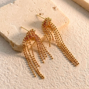 Close-up of elegant gold tassel drop earrings on natural stone background decor