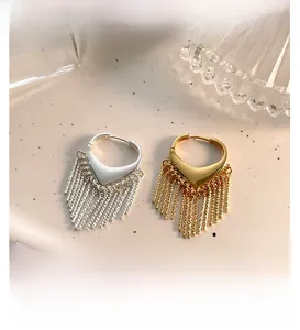 Détail macro de boucles d'oreilles cœur à pompons dorés et argentés sur pierre