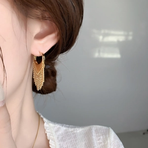 Détail de boucles d'oreilles cœur à pampilles dorées montrant le mouvement élégant