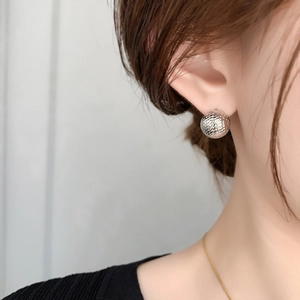 Macro detail of textured silver round stud earring featuring scale pattern on female model