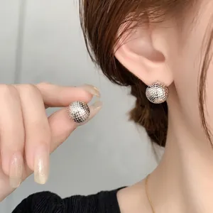 Spherical geometric mesh earrings in 18k gold plating showing on ear and hand