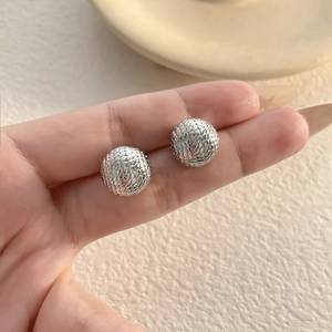 Macro view of silver mesh sphere earrings with intricate textured snake scale pattern