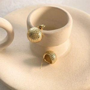 Close-up of 18k gold mesh sphere earrings with textured snakeskin pattern detail
