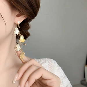 Detail of layered gold butterfly tassel earrings with sparkling zircon on a female model