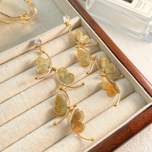 Macro view of golden butterfly earrings with zircons and fine metallic wing textures