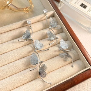 Macro shot of silver butterfly tassel earrings with zircon studs in a luxury jewelry box