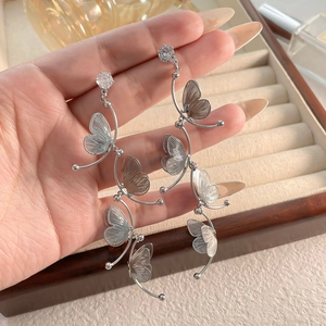 Detail of silver butterfly tassel earrings with sparkling cubic zirconia on a jewelry box