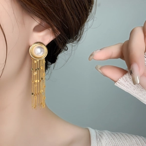 Detail of long gold tassel earrings with white pearl and layered sequin chains on model