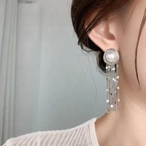 Macro shot of silver tassel earrings with a large pearl and cascading metallic sequins