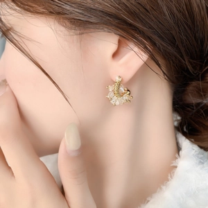 Macro shot of U-shaped gold earrings with sparkling crystals on a female model's ear